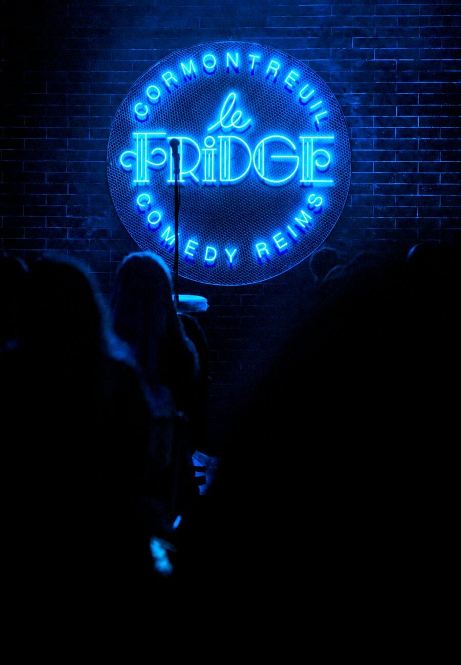 La scène du Fridge Comedy Reims Cormontreuil, logo néon au mur